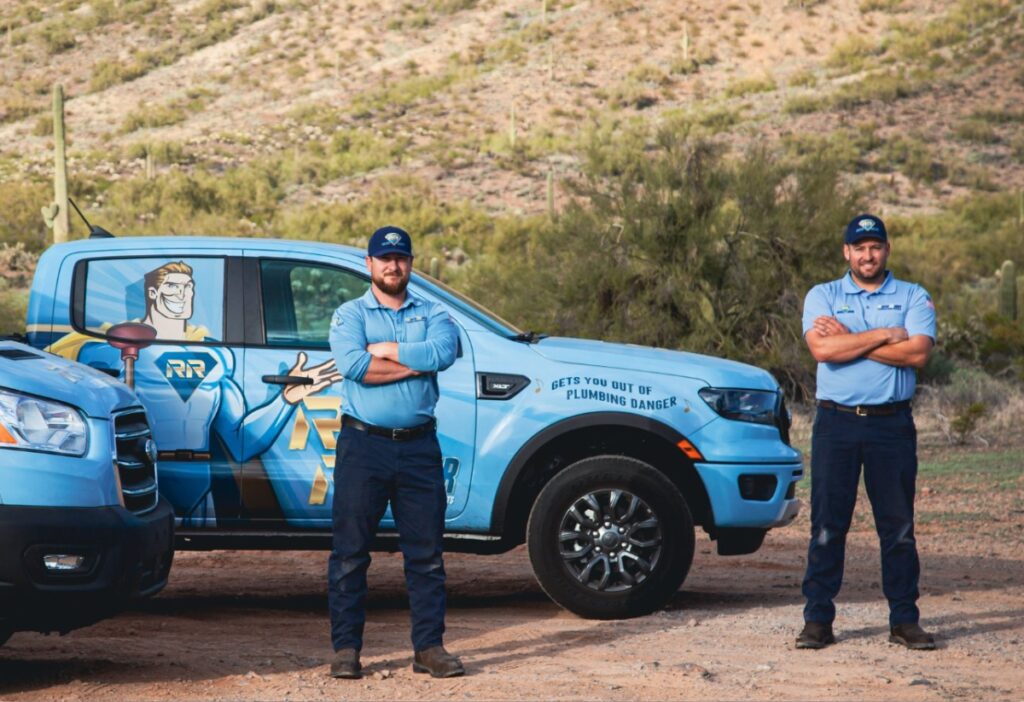 Plumbers from Rooter Ranger Standing Near Service Trucks